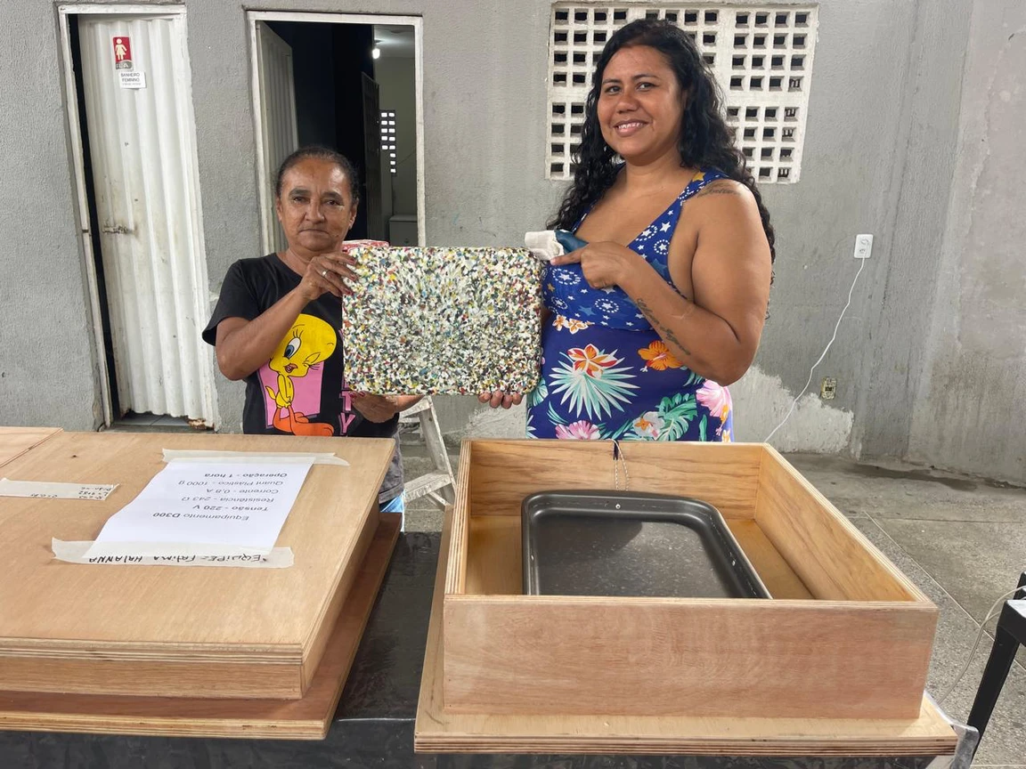 Duas mulheres apresentando uma placa de plástico transformado na oficina